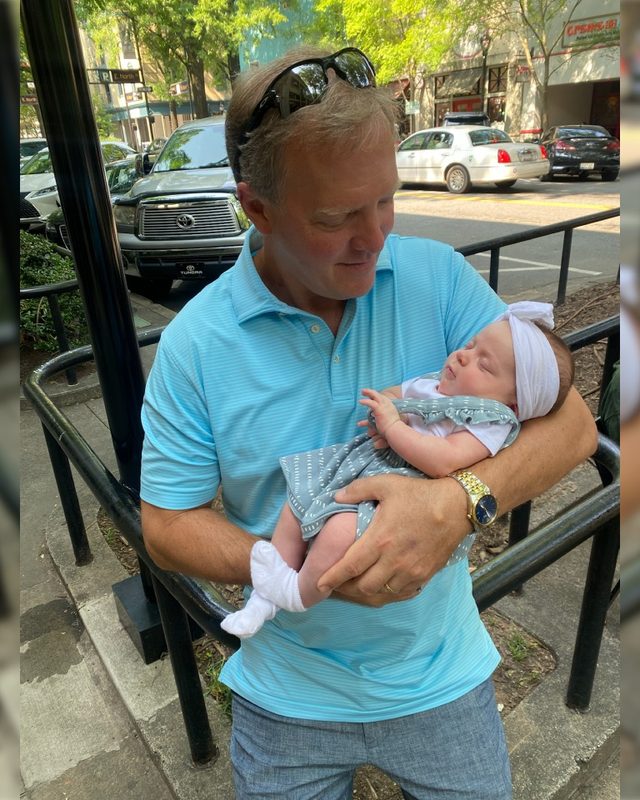 Scott Allison holding a sleeping baby on a downtown sidewalk